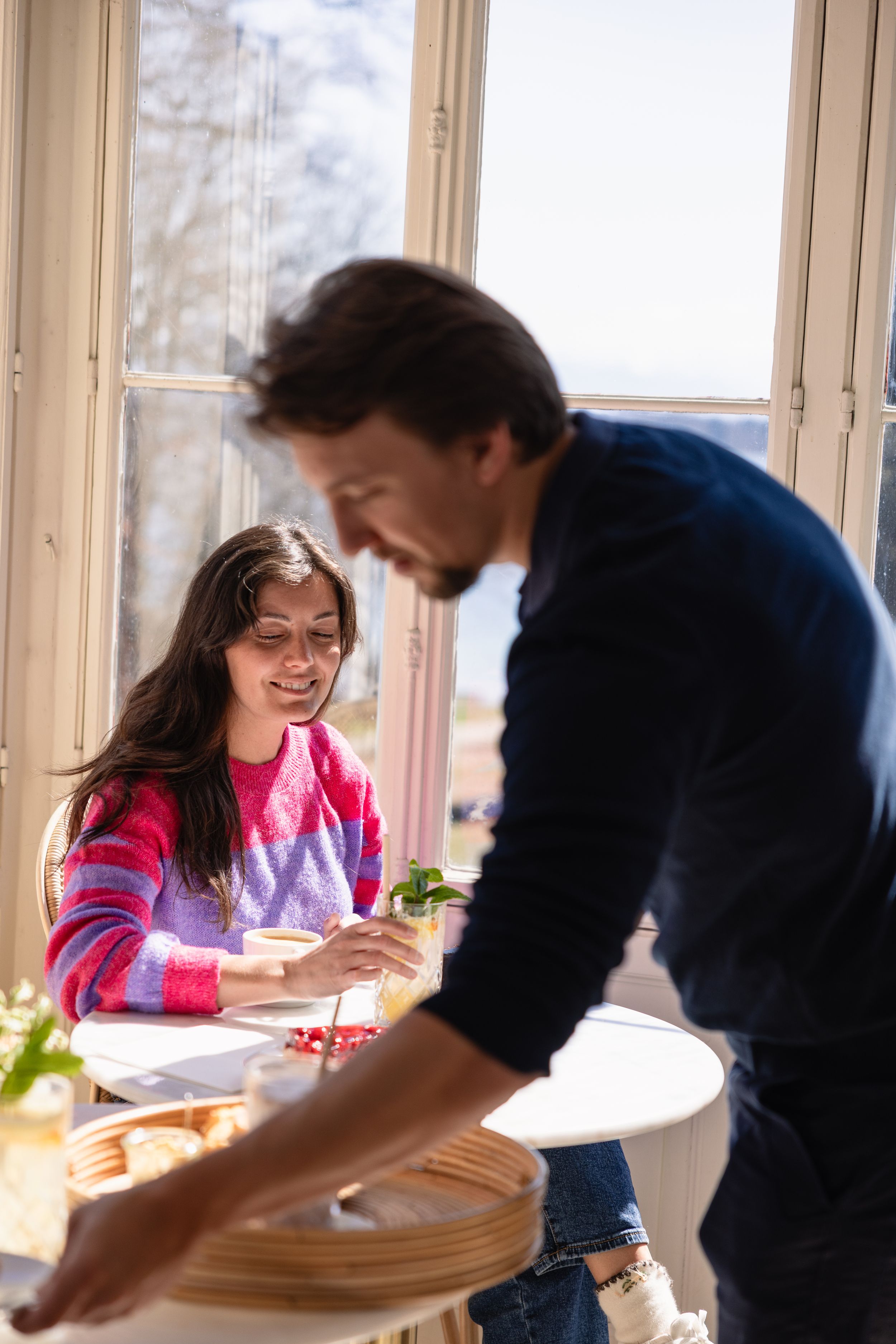 Couple enjoying light-hearted moment at sunny window table.