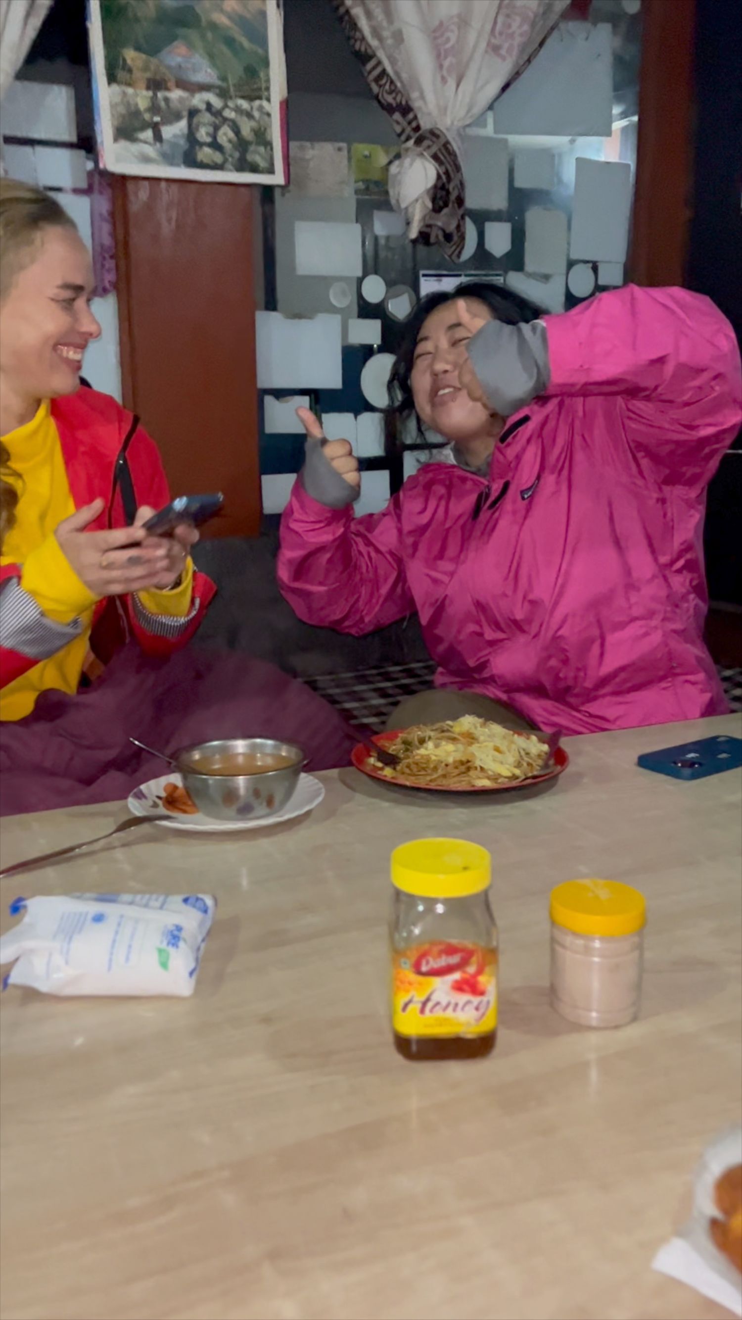 Group enjoying a meal together at a rustic table with honey and snacks visible.