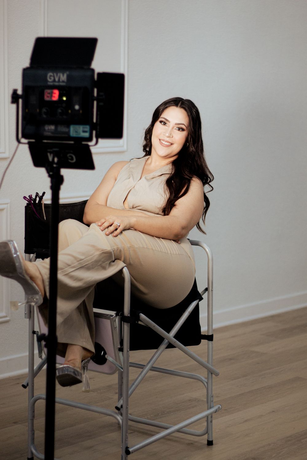 A professional photo shoot setup with a high director's chair and video light in a minimal studio space.