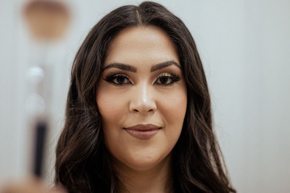 Close-up beauty portrait of a young woman with long dark hair and natural makeup smiling at the camera.