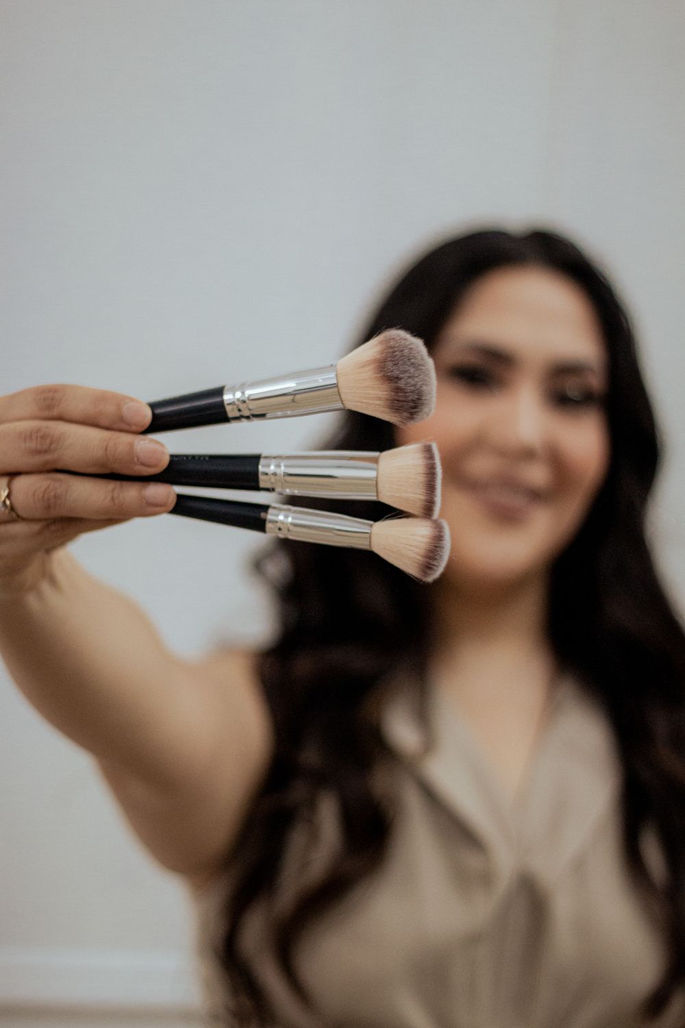 A makeup brush set being held up against a blurred background showing soft bristled professional brushes.