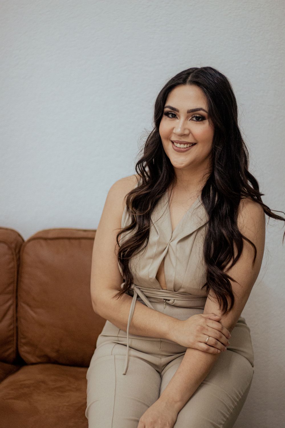 Lifestyle photo of someone in beige outfit sitting on brown leather couch.