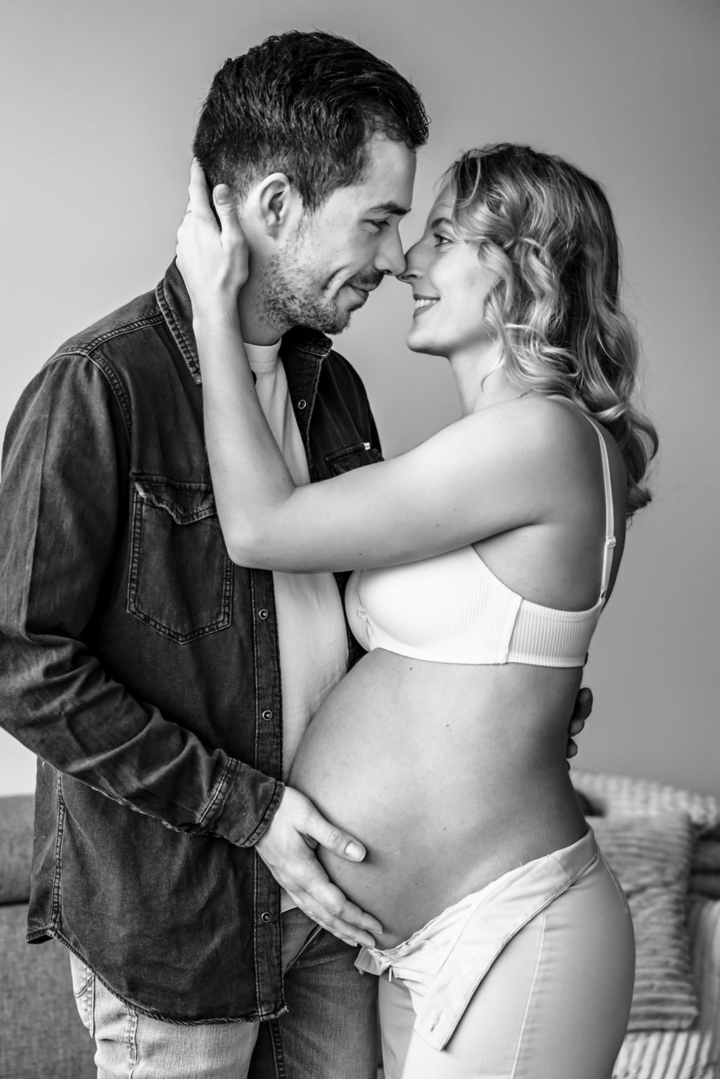 Intiem moment tussen aanstaande ouders tijdens een zwangerschapsshoot thuis in Noord-Holland.