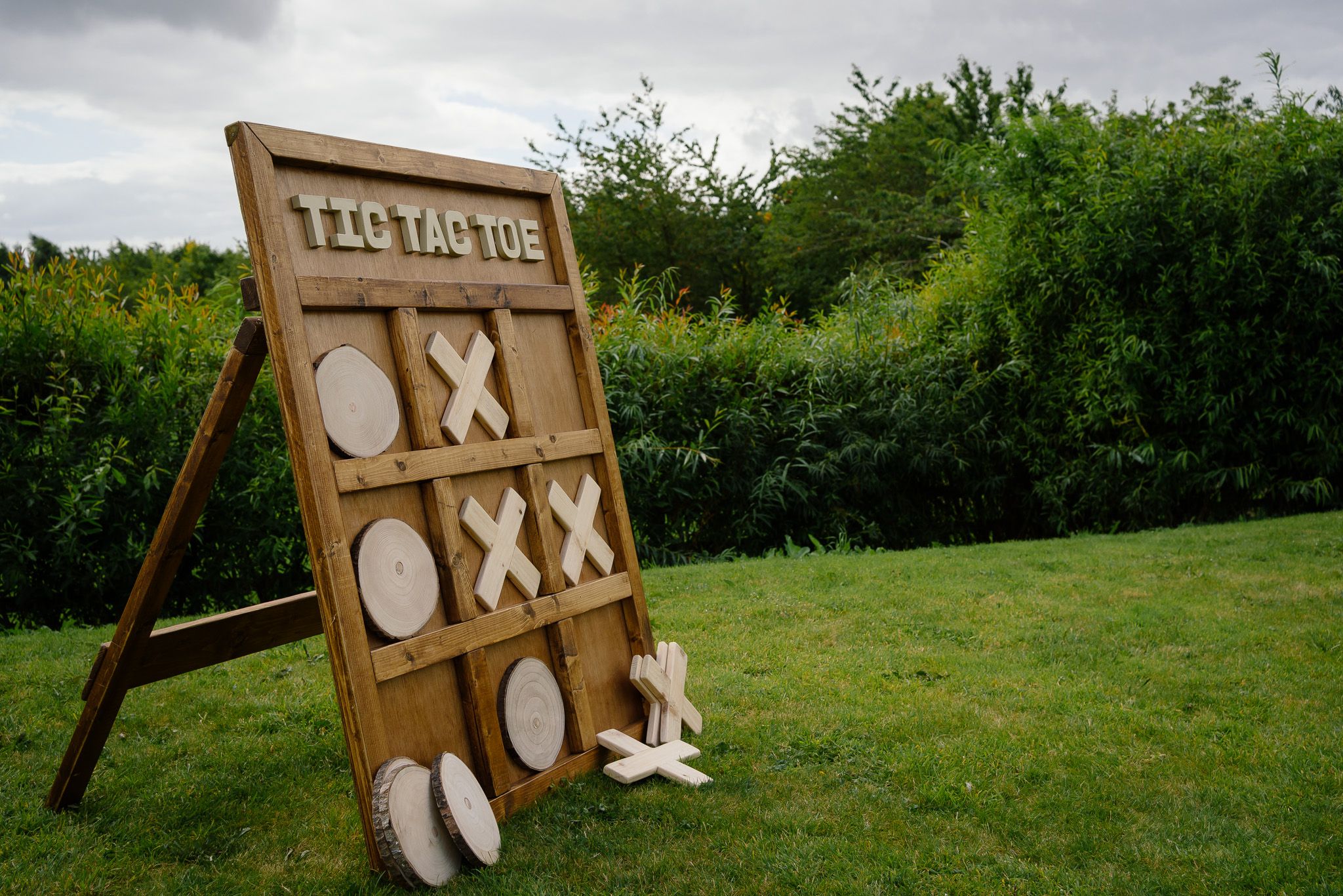 A series of wooden signs in a grassy field spell out "XX" with rustic styling and natural surroundings.