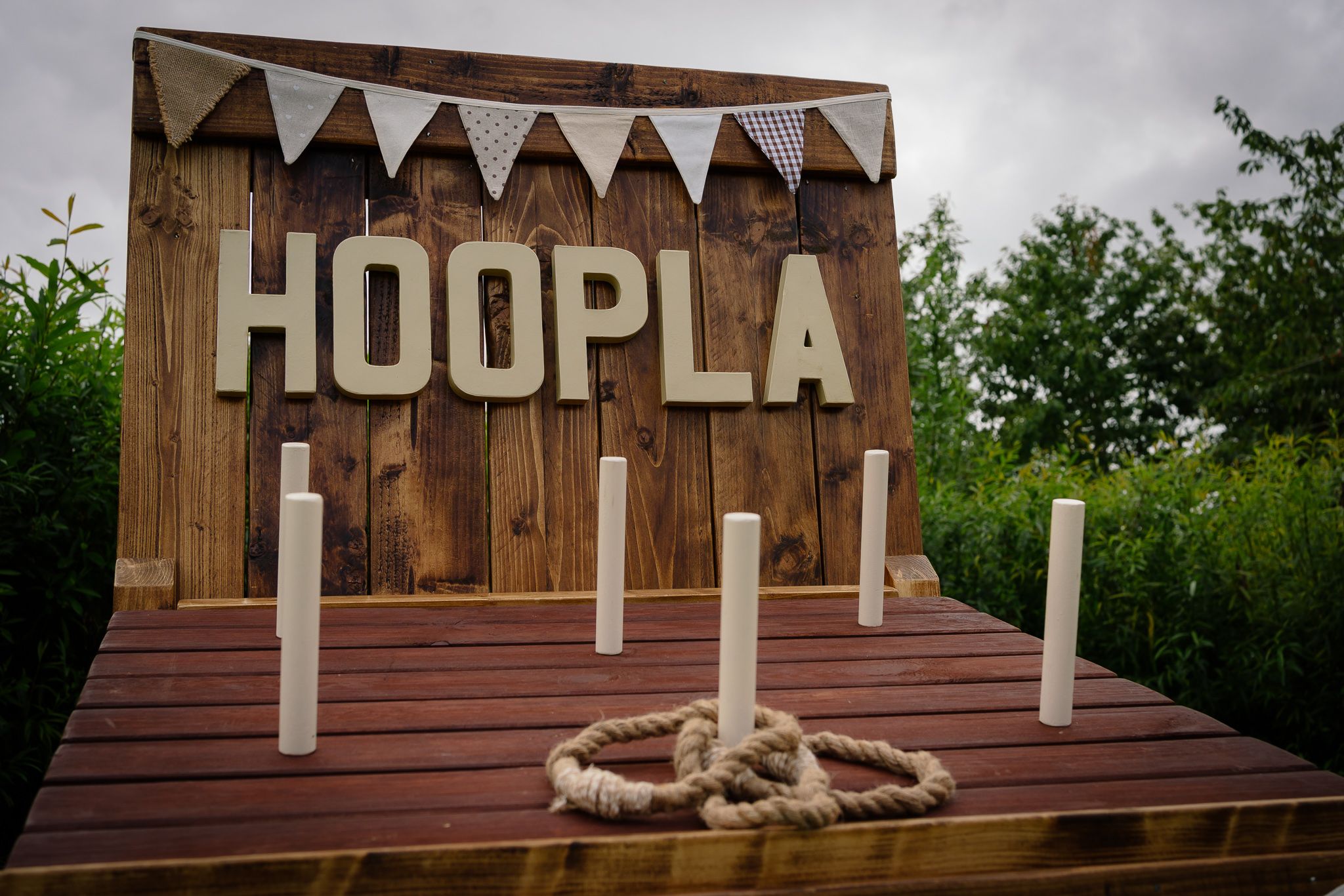 A rustic wooden sign reading 'HOOPLA' mounted on a brown wall with decorative zigzag patterns above.