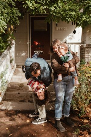 Candid family interaction on front porch steps surrounded by lush foliage.