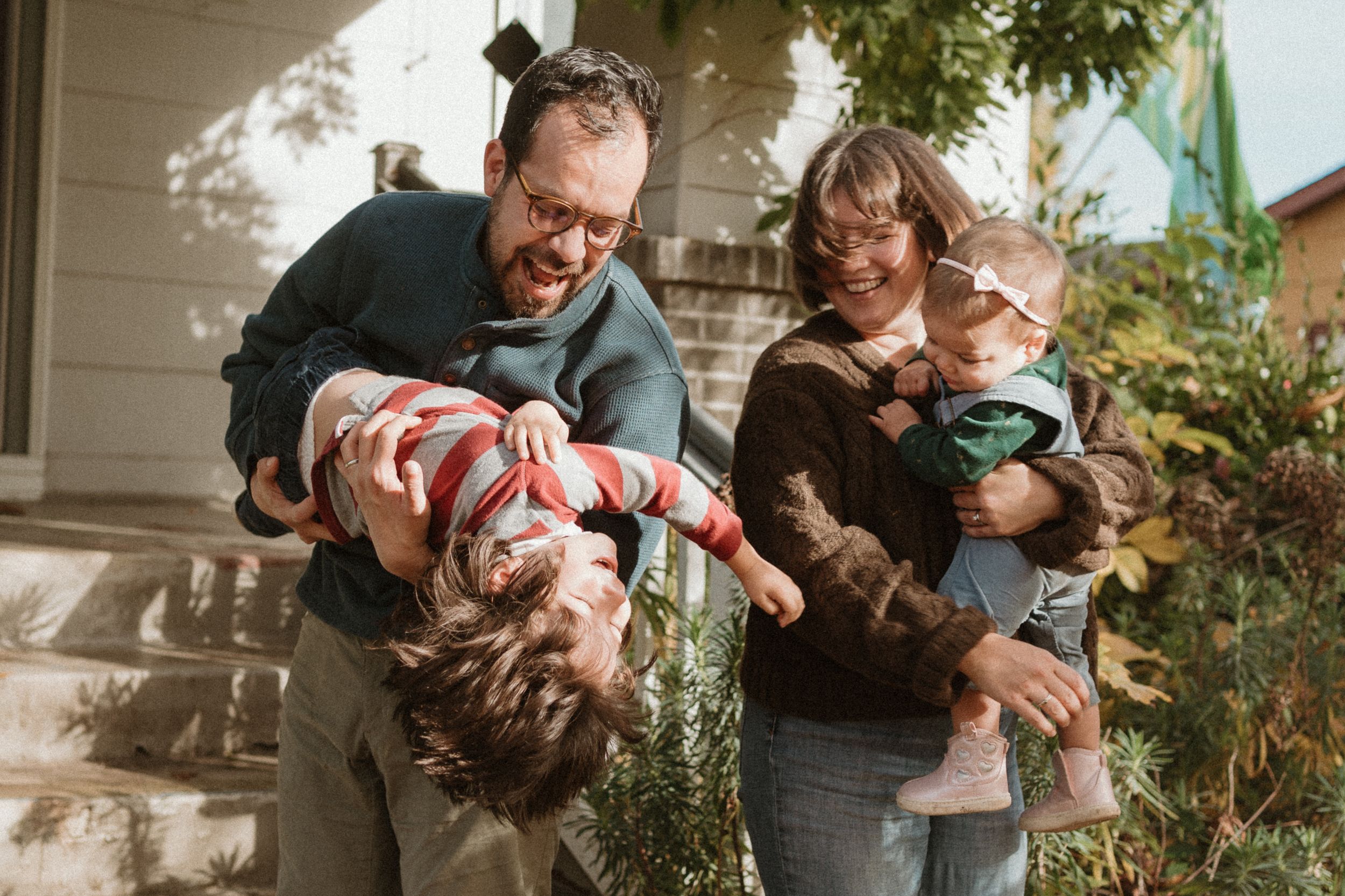 Joyful outdoor family portrait showing playful interactions on house steps.