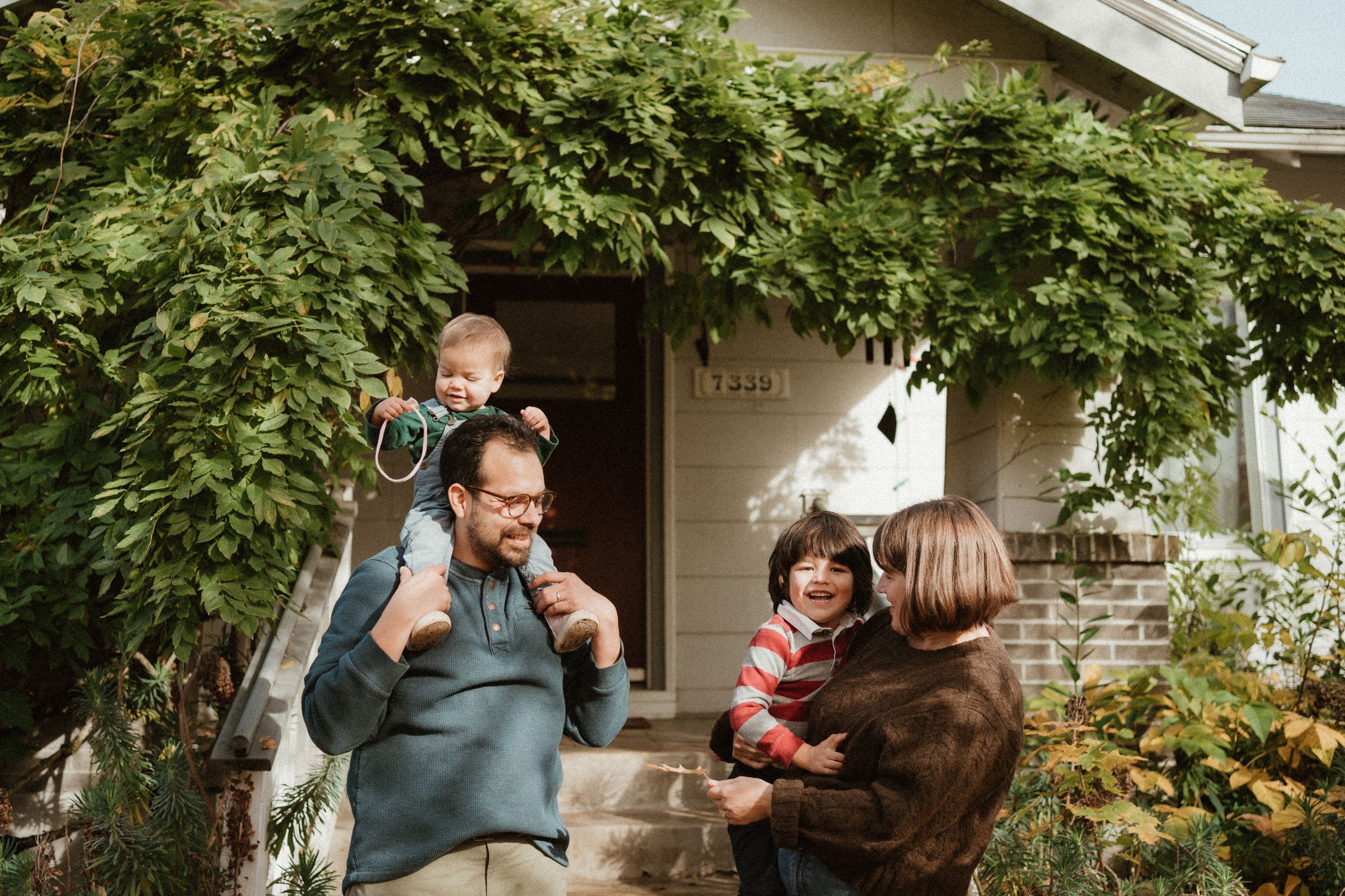 Casual family portrait with natural expressions outside home entrance.