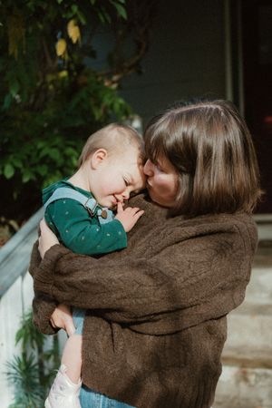 Tender moment between parent and child on front steps with natural lighting.