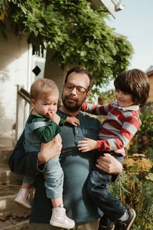 Heartwarming interaction between family members on outdoor steps with lush greenery in background.