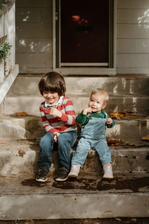 Two people sitting together on concrete steps sharing a sweet moment in autumn.