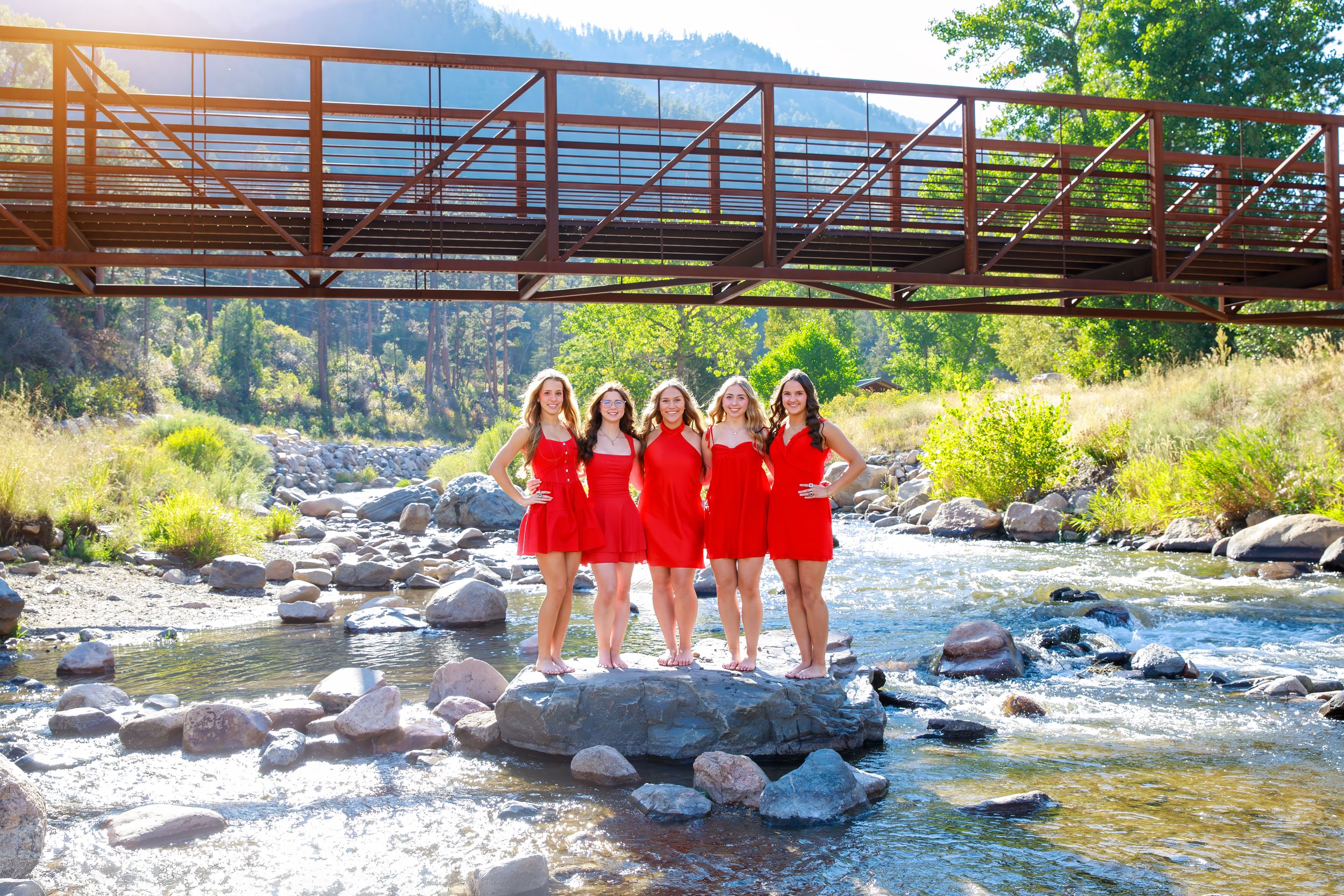 A series of photos showing people posing on rocks near a flowing river with a rustic bridge in the background.