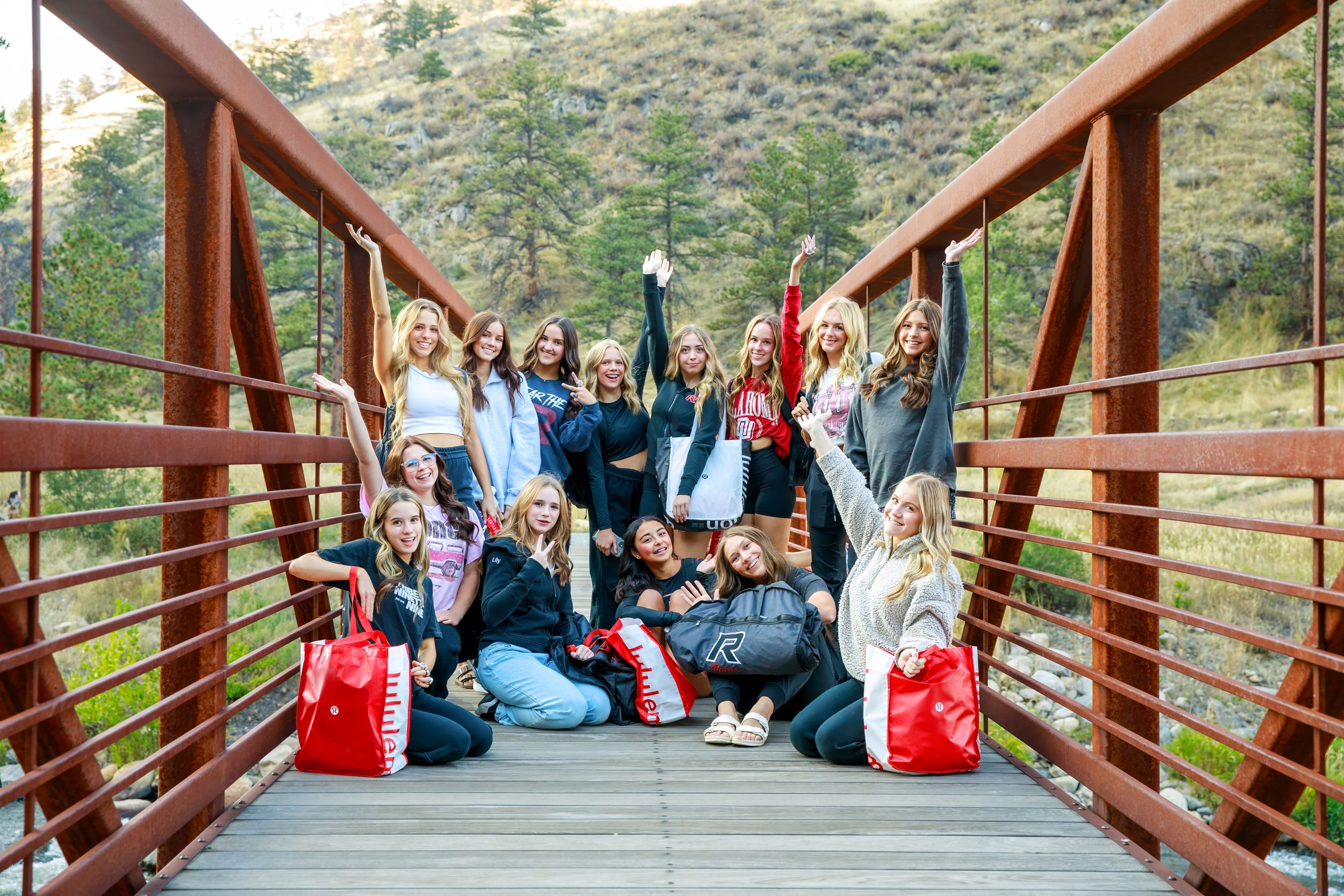 Group gathered on a wooden bridge in a mountain setting for outdoor event photography.