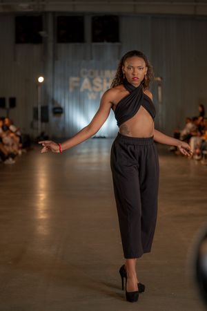 Modern black halter crop top and culottes ensemble presented on fashion runway.