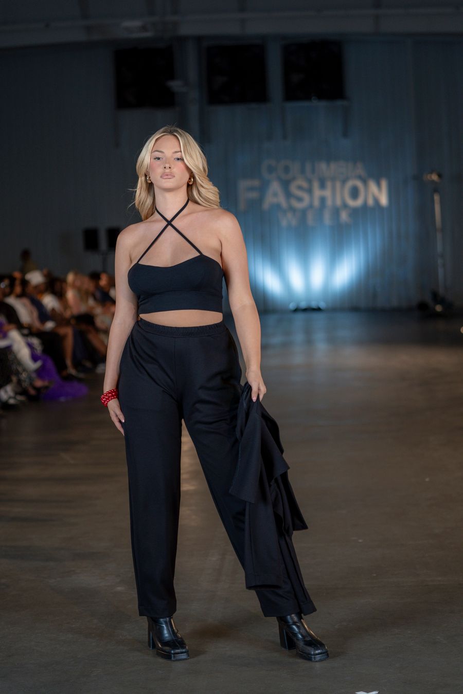 Model showcases black crop top and wide-leg pants ensemble at fashion show.