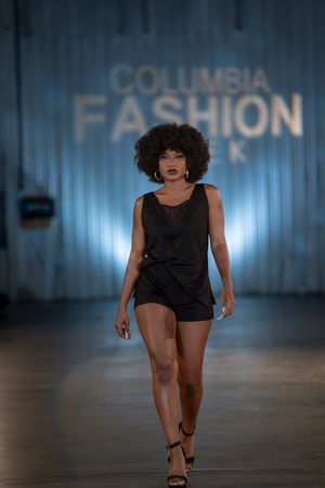 Model struts down Columbia Fashion Week runway in chic black romper.