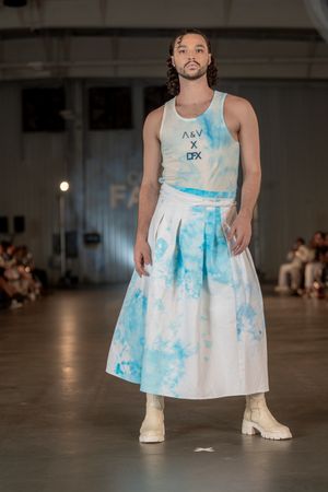 Model presents tie-dye blue and white dress with platform boots on runway.