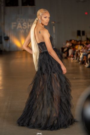 Dramatic black tulle ball gown with strapless design displayed on fashion runway.