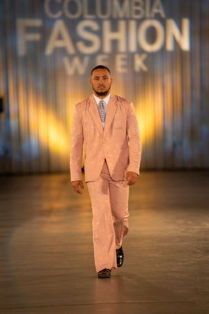 A salmon pink suit with matching tie walks the runway at Columbia Fashion Week.