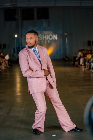 A model showcases a pink textured suit with wide-leg pants at Columbia Fashion Week.