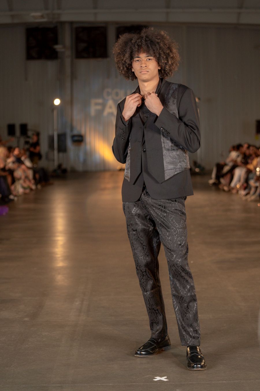 Dark grey textured suit ensemble presented on illuminated fashion runway.