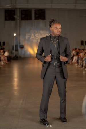A model presents a charcoal grey suit with layered necklaces at Columbia Fashion Week.