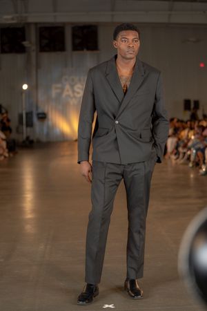 A model presents a classic grey suit with an open collar at Columbia Fashion Week.