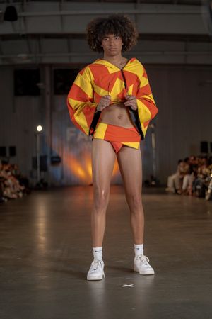Yellow and red sporty outfit with cropped top and shorts paired with white sneakers on fashion runway.