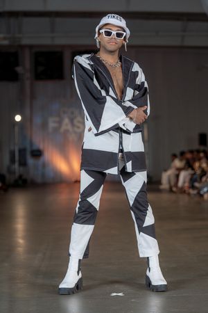 Model struts runway in black and white geometric print outfit with matching boots.