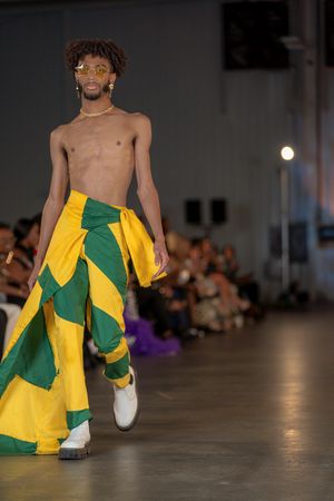 Dramatic yellow and green flowing garment displayed on fashion runway.