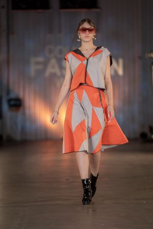 Fashion model presents geometric orange and grey mini dress on catwalk.