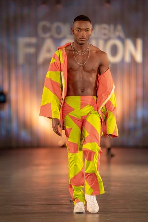 Model showcases neon yellow and coral streetwear ensemble on fashion runway.