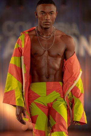 Model presents vibrant coral and neon yellow geometric print outfit on runway.