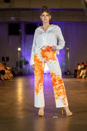 White and orange tie-dye pants paired with crisp white top on fashion runway.