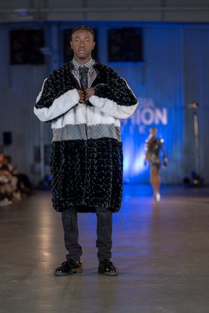 Two-tone black and white fur coat styled with dark pants on fashion runway.