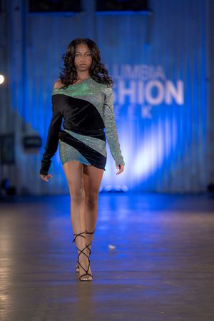 Model walks runway in color-block mini dress with lace-up sandals.