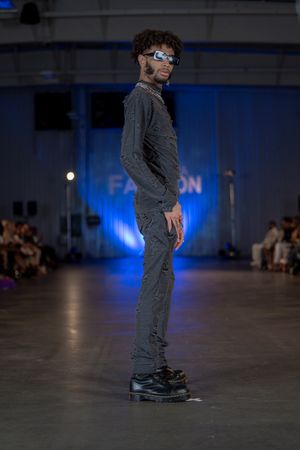 Edgy all-grey outfit with sunglasses and platform boots on fashion runway.