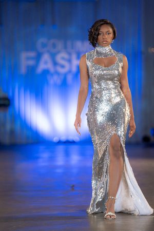 Glamorous silver sequined gown with high slit and mock neck detail on illuminated runway.