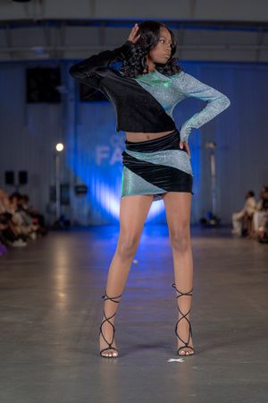 Model poses in metallic green and black athletic wear with lace-up sandals.