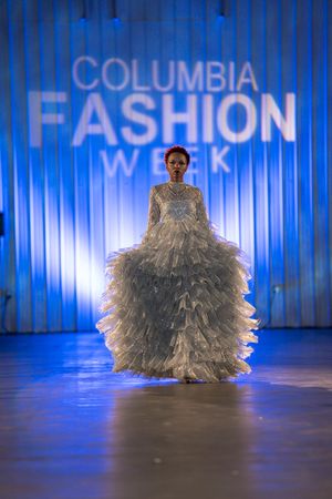 Ethereal silver feathered gown glimmers under blue runway lights.