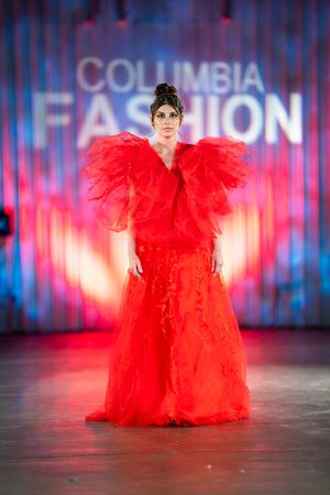 A dramatic red tulle gown with voluminous ruffled shoulders shown on the Columbia Fashion Week runway.