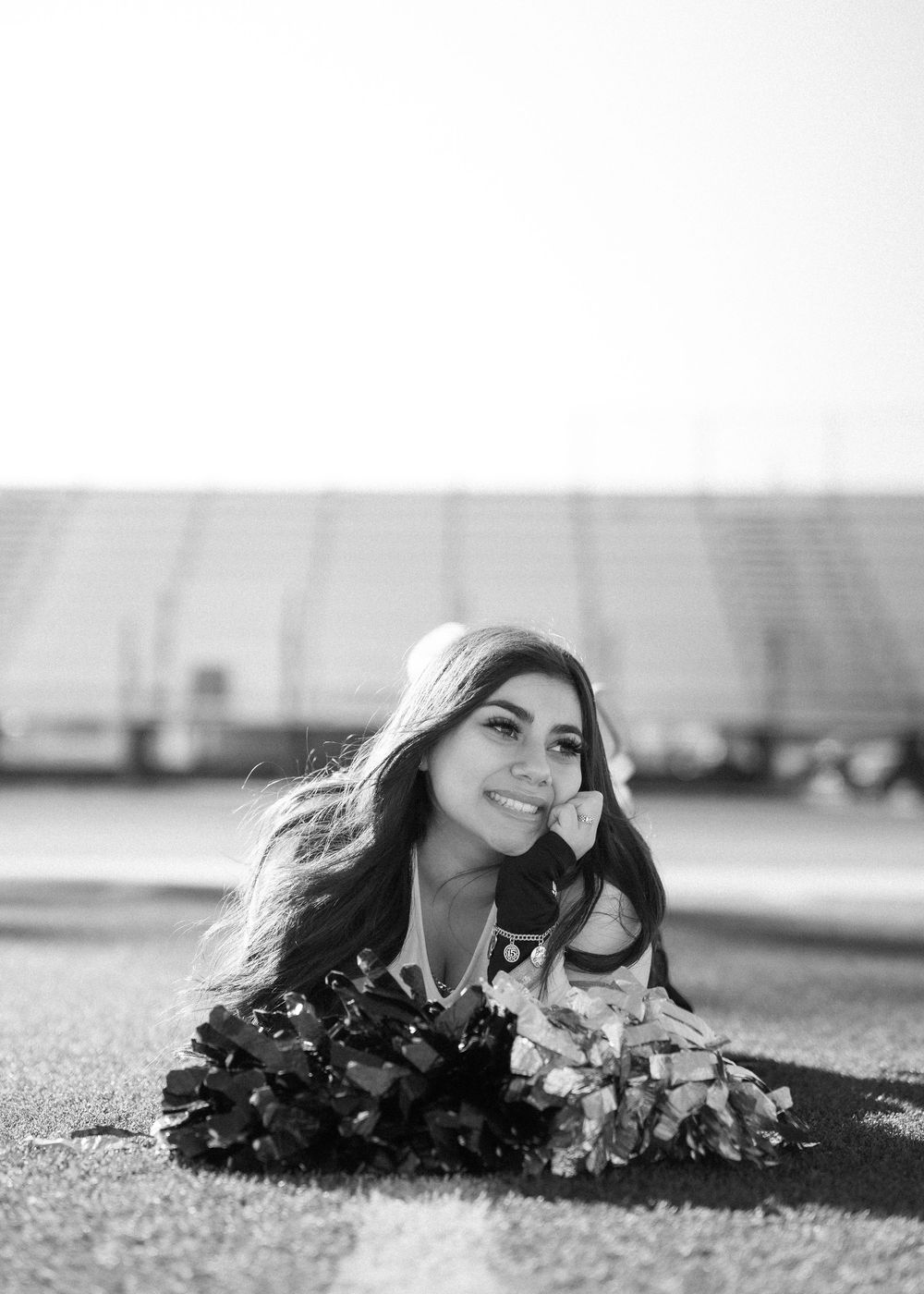 CyPark High cheerleader posing on football field with pom-poms, smiling in uniform