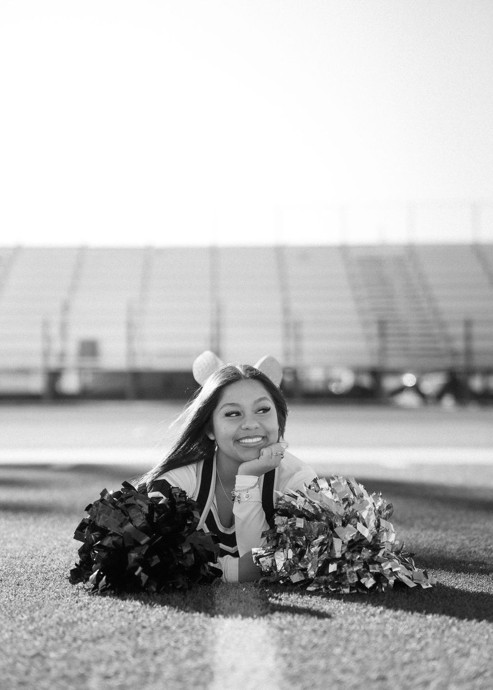 CyPark High cheerleader posing on football field with pom-poms, smiling in uniform