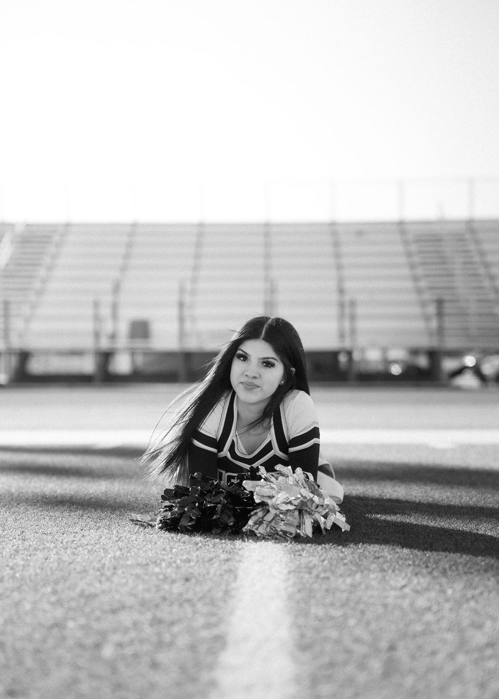 CyPark High cheerleader posing on football field with pom-poms, smiling in uniform
