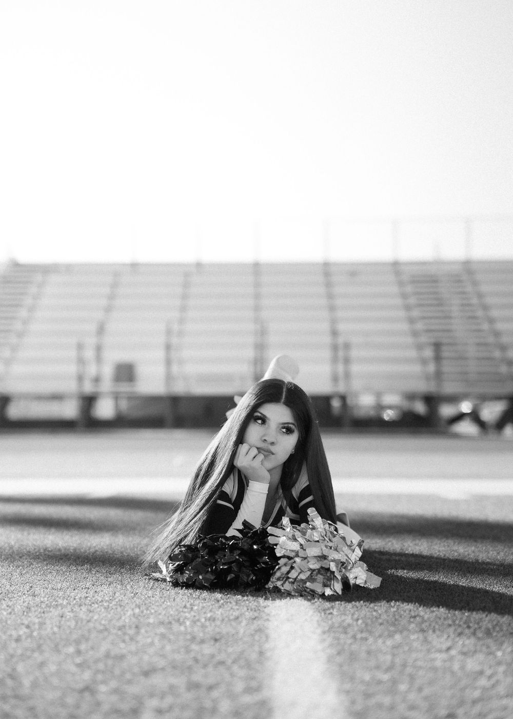 CyPark High cheerleader posing on football field with pom-poms, smiling in uniform