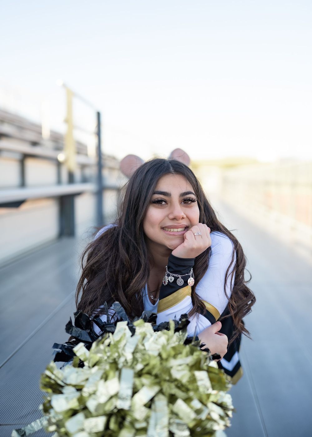 CyPark High cheerleader posing on football field with pom-poms, smiling in uniform
