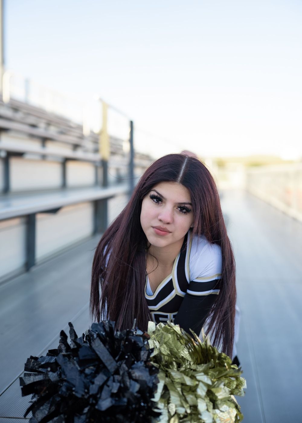 CyPark High cheerleader posing on football field with pom-poms, smiling in uniform