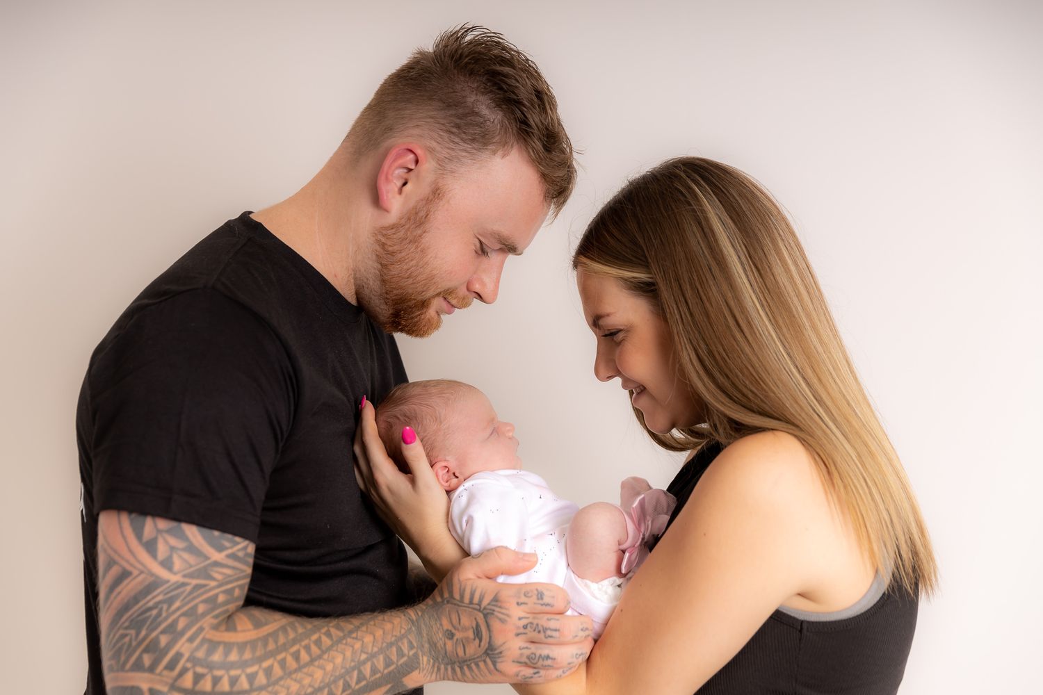 A tender moment between two people sharing an intimate embrace while holding a newborn baby.
