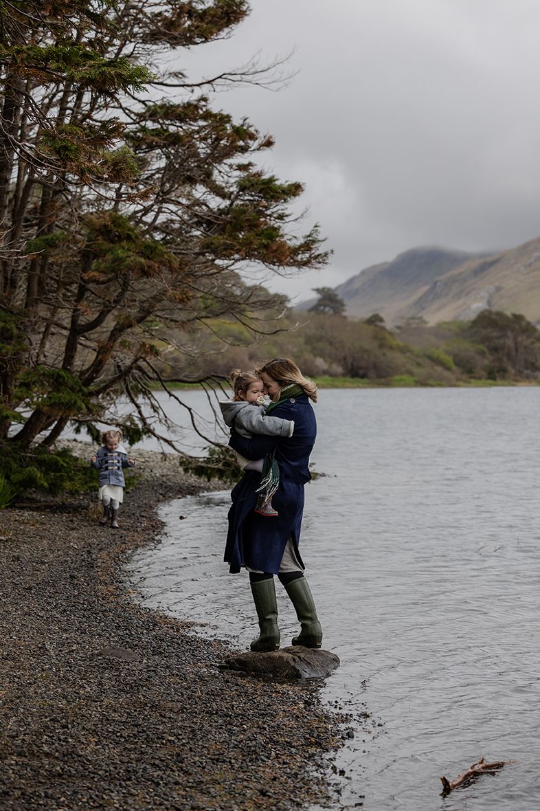 mother standing holding her daughter near Kylemore Abbey lake shore