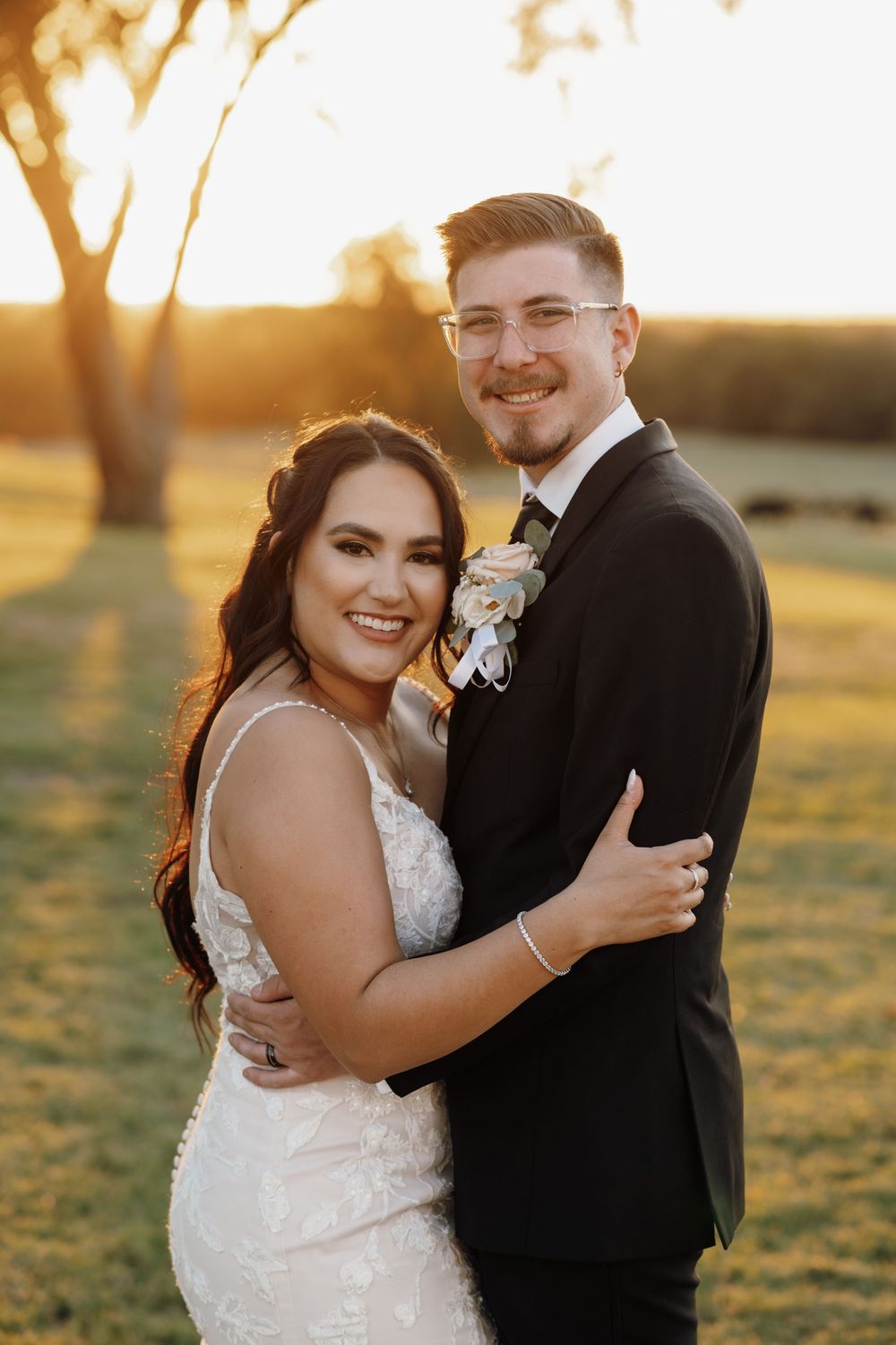 Romantic sunset wedding photos show couple embracing in a golden field during magic hour.